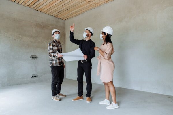 quipo de arquitecto, ingeniero y constructor con cascos de seguridad, revisando planos en una obra, enfatizando la profesionalidad en reformas